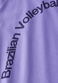 Ljubičasta tkanina s natpisom "Brazilian Volleyball" u podebljanim crnim slovima, koja prikazuje glatku teksturu i moderan, sportski dizajn.