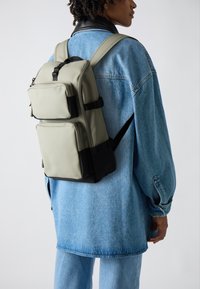 Zweifarbiger Rucksack in Hellgrau und Schwarz, aus glattem Material gefertigt. Verfügt über mehrere Reißverschlussfächer und verstellbare Träger.