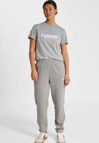 Grå T-shirt med kort ärm med "hummel"-logotyp tryckt i vitt, ihopparad med matchande grå sweatpants med elastisk midja och logodetalj.