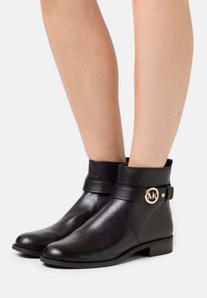 Bottines en cuir noir à bout rond, avec une bride à boucle et un détail logo doré. Texture lisse et talons blocs bas.