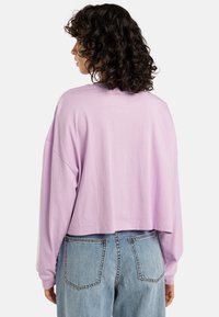 Cropped long-sleeve T-shirt in light purple cotton with a relaxed fit, featuring a round neckline and dropped shoulder seams.