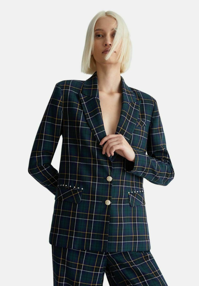 Blazer a quadri verdi con accenti gialli e bianchi, dotato di colletto a rovescio, due tasche frontali con dettagli borchiati e chiusura a due bottoni.