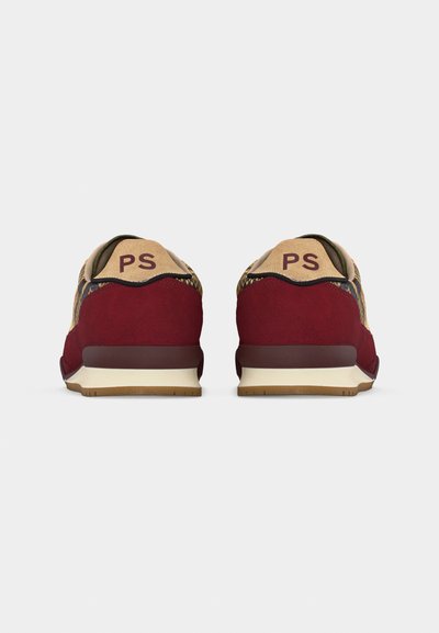 Ζευγάρι κόκκινων σουέντ και sneakers με σχέδιο, που φαίνονται από πίσω, με μπεζ ταμπελάκια στη φτέρνα με τα γράμματα "PS".