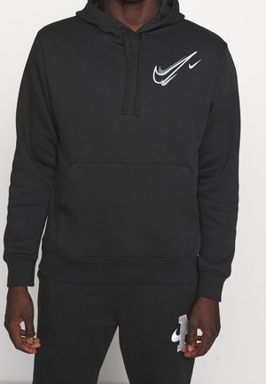 Czarna bluza z kapturem i spodnie dresowe z srebrnymi i białymi logo Nike, noszone przez osobę na jasnym, jednolitym tle.