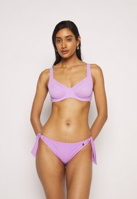 Conjunto de bikini lilás com um top estruturado com aro e alças largas, e calções laterais com laço a condizer. Tecido suave com detalhe de hardware mínimo.