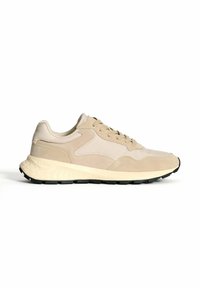 Zapatilla beige con parte superior de ante y malla, punta redonda, cierre con cordones y suela texturada. Presenta un sutil logo en el lateral.