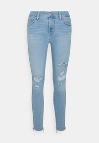 Jeans ajustados de un azul claro hechos de mezclilla, con detalles desgastados que incluyen rasgaduras y dobladillos deshilachados, ofreciendo una silueta ceñida.