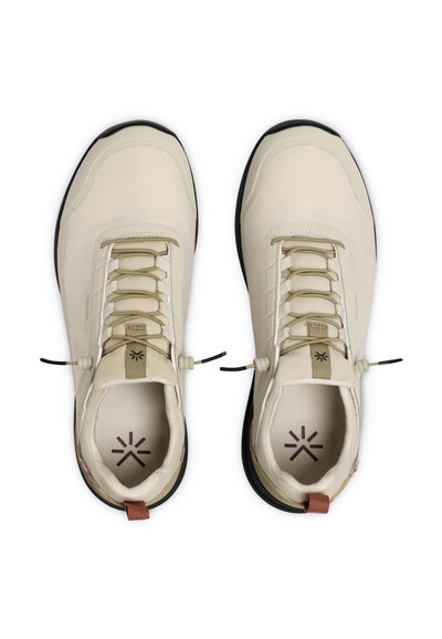 Paire de baskets décontractées beiges avec semelles noires et lacets élastiques sans nouer, vues de dessus sur fond blanc.