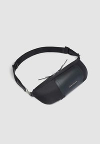 Riñonera negra hecha de tela y cuero, con una textura suave, una forma elegante y un cierre de cremallera con un acento de logo en la parte frontal.