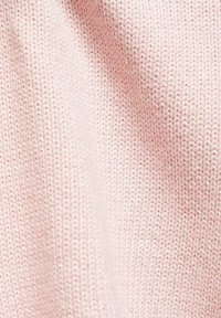 Hellrosa gestrickter Stoff mit einem dichten, strukturierten Muster und sichtbaren Stichen, die ein weiches und gemütliches Erscheinungsbild erzeugen.