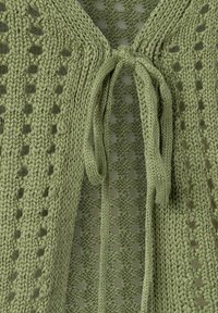 Gebreide cardigan in lichtgroen met een gestructureerde open weving. Beschikt over een sluiting met een voorknoop en verlengde mouwen, wat ademend vermogen en stijl benadrukt.