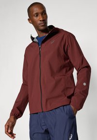 Bordeaux leichte Jacke mit Reißverschluss, elastischen Bündchen und reflektierenden Akzenten. Sie lässt sich gut mit marineblauen Hosen kombinieren und zeichnet sich durch ein modernes Design aus.