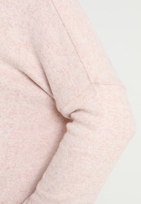 Helles rosa Sweatshirt aus einem weichen, strukturierten Stoff. Verfügt über einen lockeren Schnitt und sichtbare Nähte entlang des Ärmels.