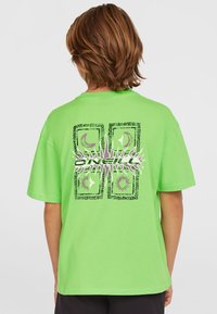 Camiseta de algodón verde con un estampado gráfico en la parte posterior que incluye formas y patrones abstractos, mangas cortas y un corte relajado.
