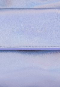 Holografisk lavendel läderplånbok med präglad "EXPATRIE"-logotyp, slät textur och minimalistisk design. Har en söm längs kanten.