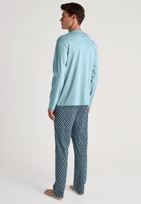 Lichtblauwe lange mouwen top en gestreepte donkerblauwe pyjamabroek met een geometrisch ontwerp, gemaakt van zachte stof. Heeft een ontspannen pasvorm.