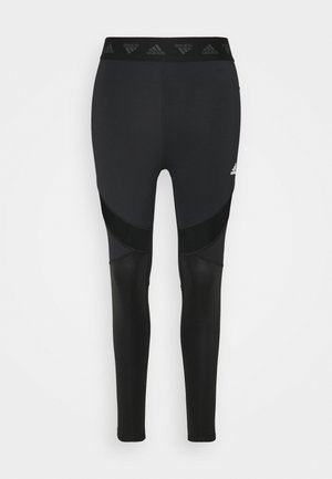 Black athletic leggings with a high waistband featuring subtle branding. The design includes mesh panels for breathability and a fitted silhouette.