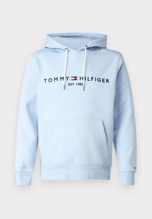 Lys blå hettegenser laget av bomull. Har en frontlomme, snorer og trykt logo "TOMMY HILFIGER EST. 1985" i mørk blå.