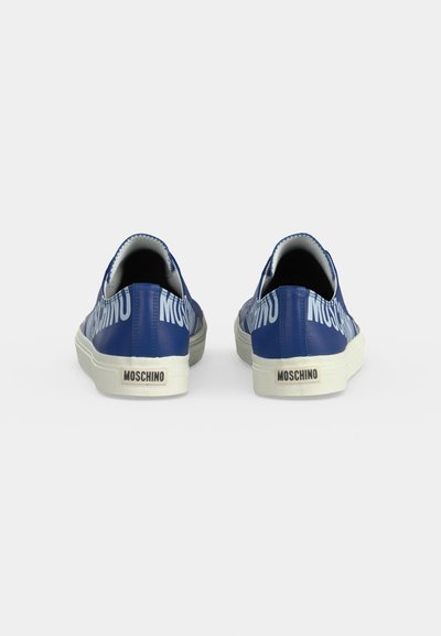 Paire de baskets slip-on bleues avec semelles blanches, comportant un grand texte "Moschino" sur les côtés et des étiquettes de marque à l’arrière.