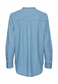 Lichtblauwe denim blouse met lange mouwen, afgeronde onderkant, achterste yoke-details en knoopmanchetten. De stof heeft een zachte, subtiele textuur.