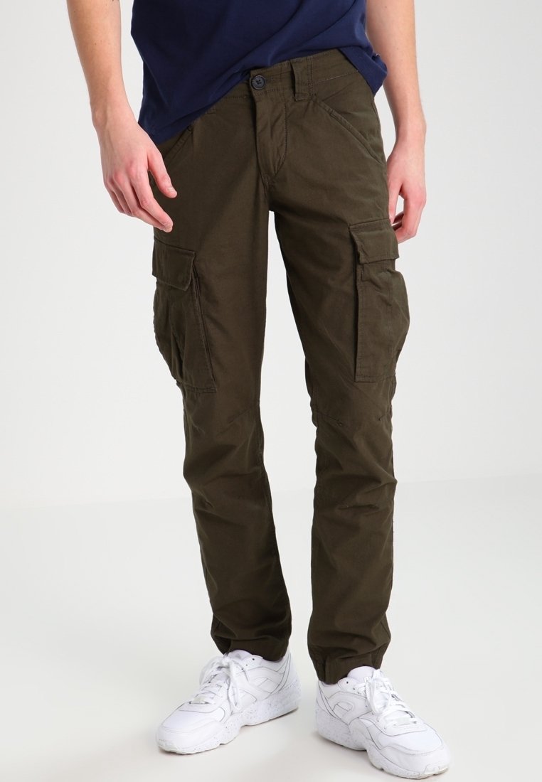 Cargo-byxor i olivgrön bomull, med stora sidofickor, avsmalnande ben och knäppning med knapp. Tillsammans med vita sneakers.