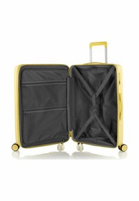 Valigia rigida gialla con zip, interno diviso da tasche in rete e cinghie incrociate, su quattro ruote girevoli, foderata in tessuto grigio scuro.