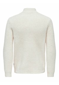 Krämfärgad, ribbad tröja med hög krage och långa ärmar. Mjuk textur med ett subtilt mönster, åtsittande vid midjan och ärmsluten.