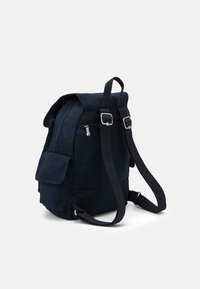 Laivastiilinen reppu, joka on valmistettu teksturoidusta kankaasta. Siinä on säädettävät hihnat, yläkansi, etutasku ja hopeiset yksityiskohdat.