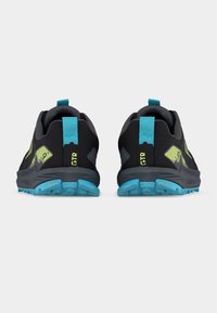 Ζευγάρι από μαύρα και μπλε παπούτσια για τρέξιμο σε μονοπάτια με νεον κίτρινα λεπτομέρειες, εμφανιζόμενα από πίσω σε λευκό φόντο.