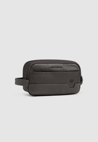 Donkergrijze toilettas van getextureerd leer met een ritssluiting, een platte handgreep en een subtiel logo aan de voorkant. Rechthoekige vorm.