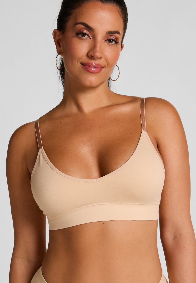 Bralette sans fil beige en tissu doux et extensible. Doté de bretelles réglables et d'un design sans coutures pour un confort optimal.