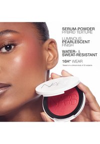 Gros plan d'une femme à la peau éclatante tenant un blush compact rouge NARS près de sa joue, avec un texte sur les caractéristiques du produit à côté.