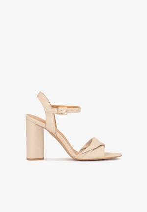 Beige hoge hakken sandaal met een geknoopt ontwerp aan de voorkant, verstelbare enkelriem en een stevige blokhak, gemaakt van soepel leer.