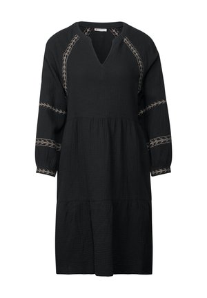 Musta mekko, jossa on V-pääntie ja kolme neljäsosapituista hihoista. Sisältää teksturoidun kankaan ja koristeellista vaaleanruskeaa brodeerausta olkapäissä ja hihoissa.