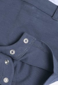 Bodysuit de algodón azul marino con una textura suave, que presenta cierres a presión plateados y un acabado de costura suave en el cuello y las aberturas de las piernas.