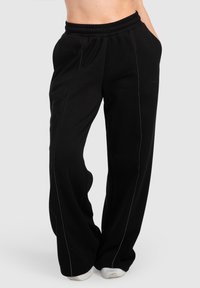 Sorte sweatpants med afslappet pasform, elastisk talje, sidelommer og kontrasterende søm. Blødt stof med en glat tekstur.