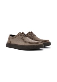 Chaussures en cuir marron avec un bout arrondi, des détails cousus et une semelle foncée texturée. Elles sont dotées de lacets et d'un design à profil bas.