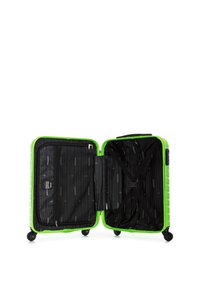 Valise rigide verte avec un intérieur noir. Caractéristiques : compartiments zippés et sangles élastiques croisées pour maintenir les objets en place.