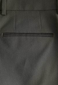 Pantaloni din țesătură gri cu un model texturat. Au un croi drept și o buzunar la spate, finisat cu material negru.