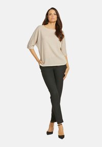 Beige textuur top met brede halslijn en driekwart mouwen, gecombineerd met zwarte slim-fit broeken en zwarte hakken. Eenvoudig en eigentijds ontwerp.