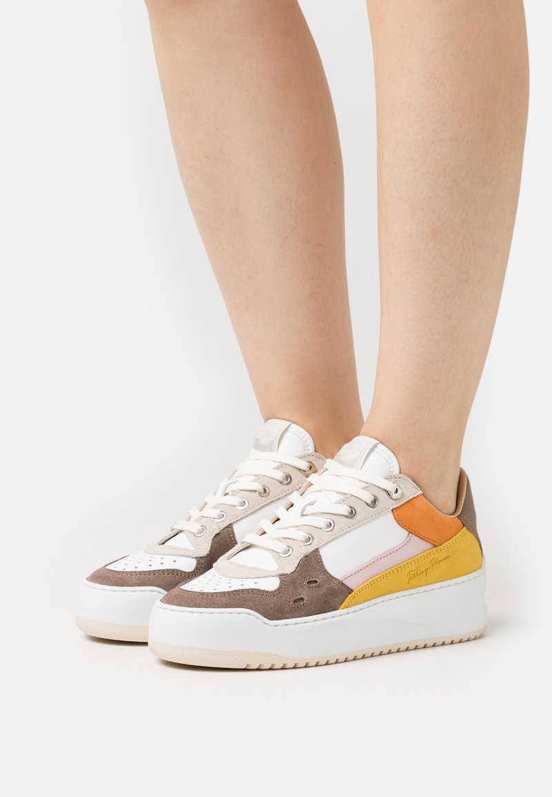 Sneakers med en blandning av beige, brunt, vitt och orange material; klassisk snörningsdesign; texturerad mocka och släta ytor; upphöjd sål.