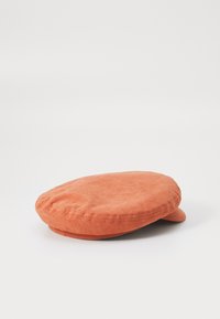 Cască din material portocalie cu o formă ovală aplatizată, având o textură netedă și o borcă mică, rotunjită. Cusături simple de-a lungul marginii.