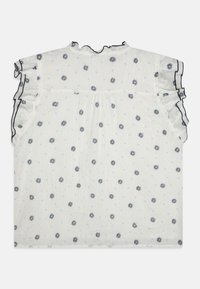 Blouse blanche avec des motifs floraux bleus, manches volantes et décolleté en forme de vague. Fabriquée en tissu texturé avec des finitions noires contrastantes.