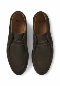 Dark brown suede loafers featuring a lace detail, rounded toe, and contrasting stitching; soft texture with a smooth interior lining.