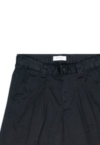 Pantalons noirs à taille plate, avec passants de ceinture et fermeture à bouton. Fabriqués dans un tissu lisse avec des plis à l'avant. Étiquette visible au niveau de la taille.