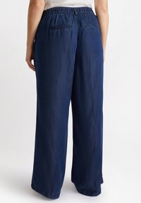 Dunkelblaue, weite Hosen mit elastischem Bund, ausgestattet mit zwei Gesäßtaschen und einer glatten Textur. Der Saumabschluss ist schlicht und sauber.