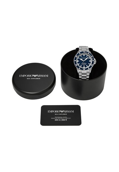 Emporio Armani Sea Explorer duikhorloge met blauwe wijzerplaat en zilverkleurige metalen band, open zwarte ronde doos en certificeringskaart.
