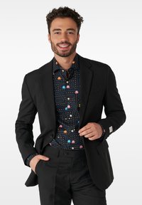 Schwarze Anzugjacke über einem mehrfarbigen Pac-Man-Musterhemd. Mit kontrastierenden Knöpfen und Akzenten an den Manschetten. Maßgeschneiderte Passform, glattes Material.