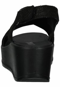 Black wedge sandal with textured adjustable strap, open back design, and a sleek platform sole. Smooth surface with minimal detailing.