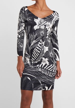 Robe à motifs noir et blanc avec des designs floraux et de feuilles, à manches longues et décolleté en V, fabriquée en tissu extensible.